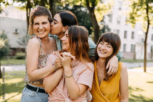 Closeup portraits of four women friends hugging and laughing, outdoors.