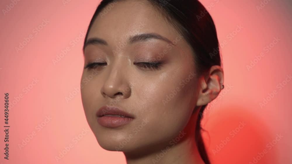 brunette young asian woman looking at camera on pink brunette young asian woman looking at camera on pink