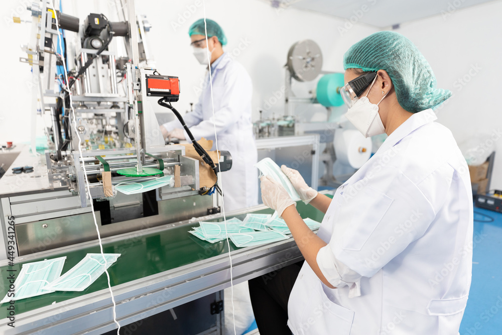 woman factory worker are producing medical face masks and checking of quality from machine woman factory worker are producing medical face masks and checking of quality from machine