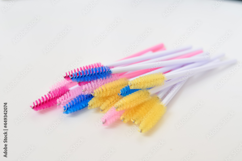 colored brushes for lash extensions in beauty salon,materials for lashmaker on white background, copy space