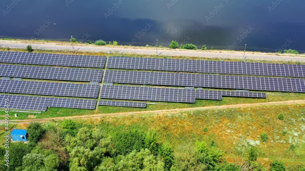 Flight over long solar panels on field. Photovoltaic solar cells near the road at bright sunny day. Alternative green energy. Aerial view Flight over long solar panels on field. Photovoltaic solar cells near the road at bright sunny day. Alternative green energy. Aerial view