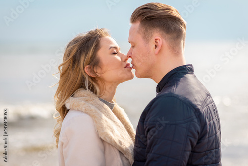 Young couple kissing outdoor.Stunning outdoors portrait of young stylish fashion couple posing in spring sea background.