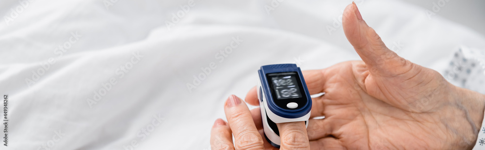 Cropped view of elderly woman using digital oximeter on hospital bed, banner Cropped view of elderly woman using digital oximeter on hospital bed, banner