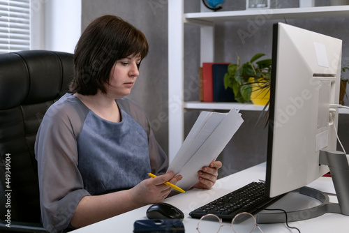 Woman works with documents at workplace in own cabinet. Director is reading contracts. Office work photo