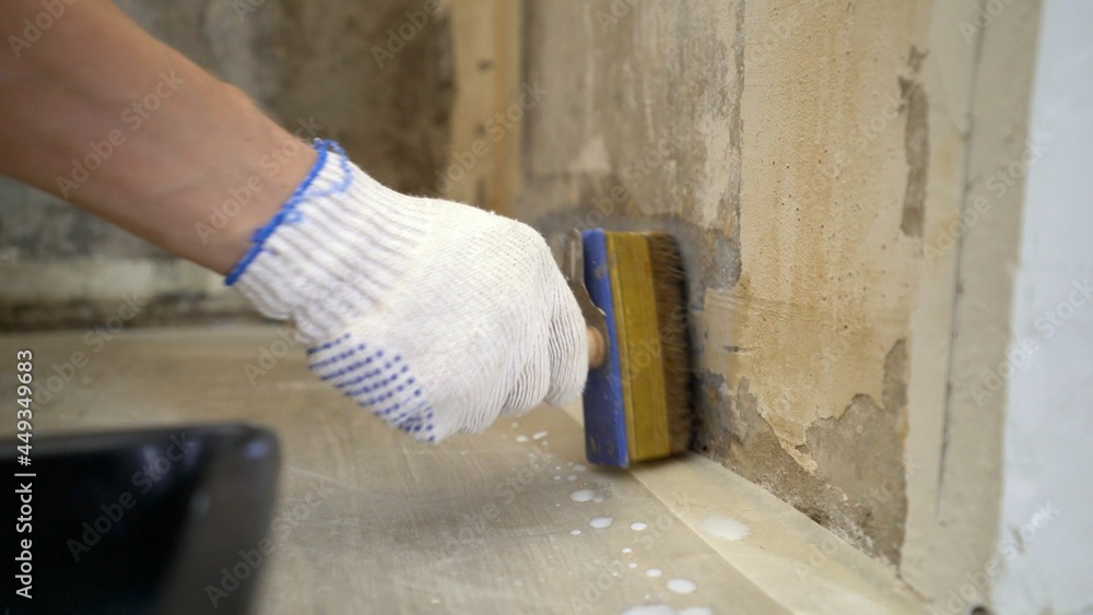 Close-up, hands holding a brush, a worker applies white primer to the wall. House-painter, hand holds a brush, draws and primed a wall. The concept of repair and decoration, painting, repair. Prime Close-up, hands holding a brush, a worker applies white primer to the wall. House-painter, hand holds a brush, draws and primed a wall. The concept of repair and decoration, painting, repair. Prime