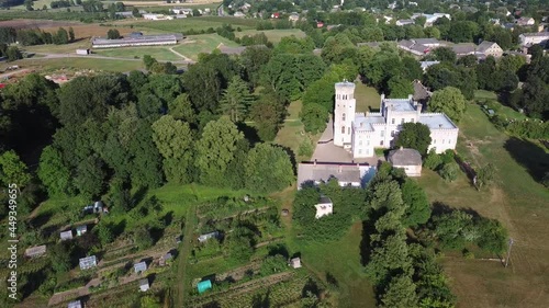 Vecauce Manor in Latvia Aerial View of the Pink Castle Through the Park. Vecauce Castle Tower With a Flying Latvian Flag. View From Above. Camera Moves Backward. Wide Shot. photo