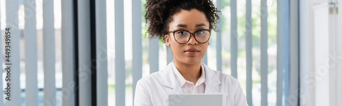 African american doctor with paper folder looking at camera, banner