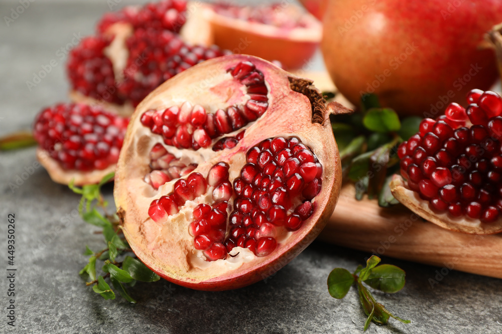 Delicious ripe pomegranates on grey table, closeup Delicious ripe pomegranates on grey table, closeup