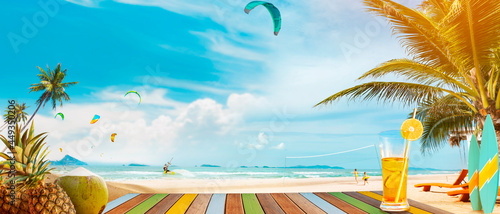 Panoramic tropical sea view. On the table are drinks and tropical fruits. A fun summer vacation getaway with outdoor activities, Kiteboarding, swimming, surfing, volleyball, and beach parties.