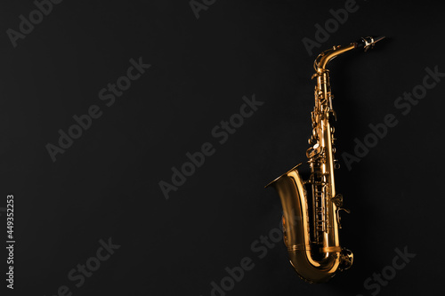 Beautiful saxophone on black background, top view. Space for text