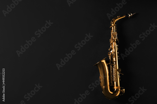 Beautiful saxophone on black background, top view. Space for text photo