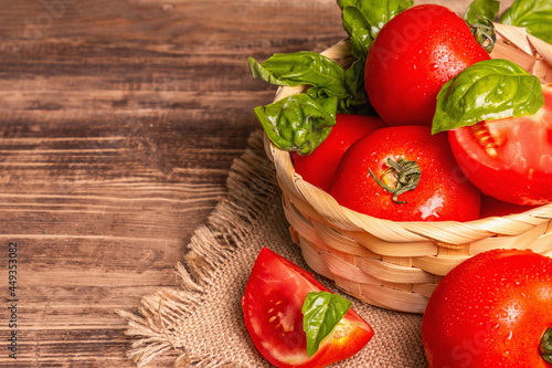 Ripe red tomatoes with fresh basil in a wicker basket