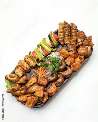 Big set of grilled meat and vegetables. Mixed food on large platter isolated on white background. Top view. Vertical format.