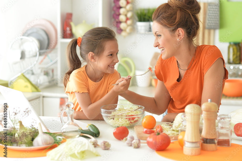Girl with her mother cooking together at kitchen table Girl with her mother cooking together at kitchen table