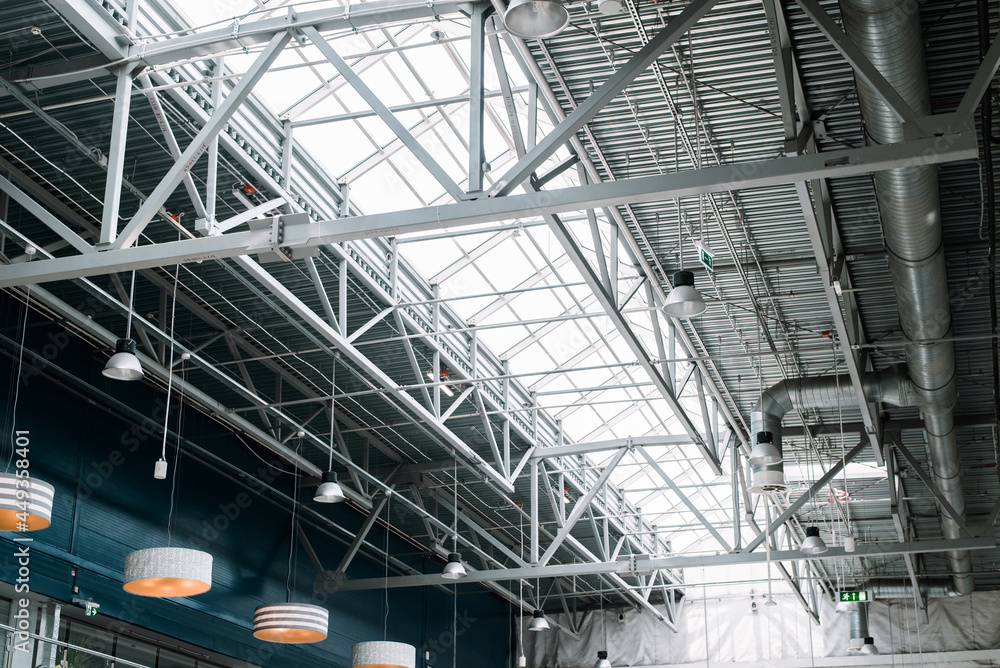 Metal roof structure of a large building, indoors. Built-in windows at the top for lighting, ventilation and lamps. Architecture and construction