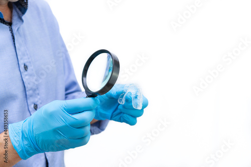 Dentist examining a dental splint with a magnifying glass. Copy space.