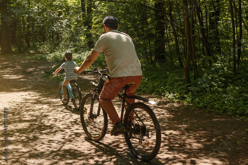 Father and son riding bicycles on a forest road. Outdoor activities and healthy lifestyle. Father's day.