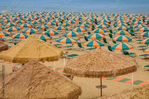 Fototapeta Naklejka Na Ścianę i Meble -  View of a sand beach full of colorful sun umbrellas without people during a sunny summer day 