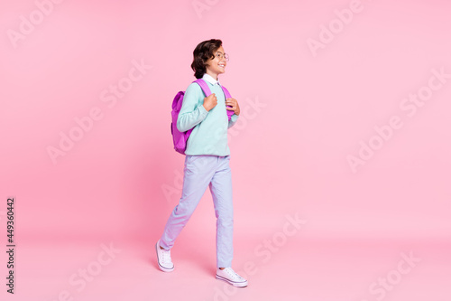 Profile photo of positive schoolboy stroll empty space wear bag specs teal shirt isolated pink color background photo
