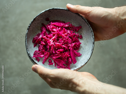 Sauerkraut from red cabbage. Vegan organic sauerkraut and kimchi recipe in a black bowl holding in two hands.