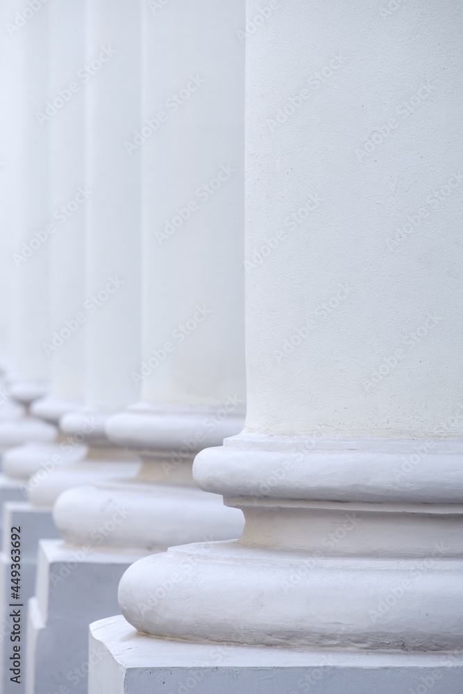 The base of the white ancient stone columns standing in a row. Selective focus. Abstract architectural background. The base of the white ancient stone columns standing in a row. Selective focus. Abstract architectural background.