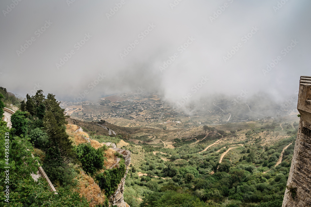 View from Erice, Sicily, Italy. Historic town on the top of mountains overlooking landscape and sea.View of beautiful lush countryside in clouds. Breathtaking panorama. Misty landscape with curvy road