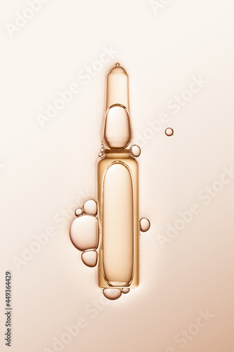 ampule with serum and bubbles around on cream-coloured background. photo