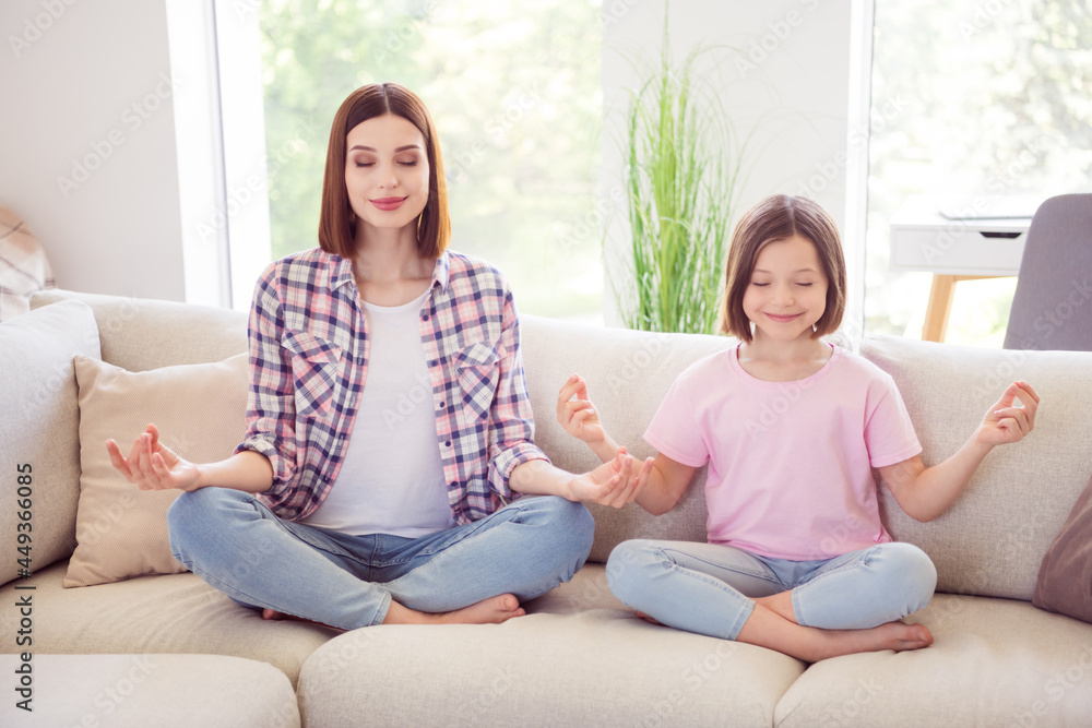 Full length photo of happy calm peaceful siblings sisters sit sofa meditation indoors inside house home Full length photo of happy calm peaceful siblings sisters sit sofa meditation indoors inside house home