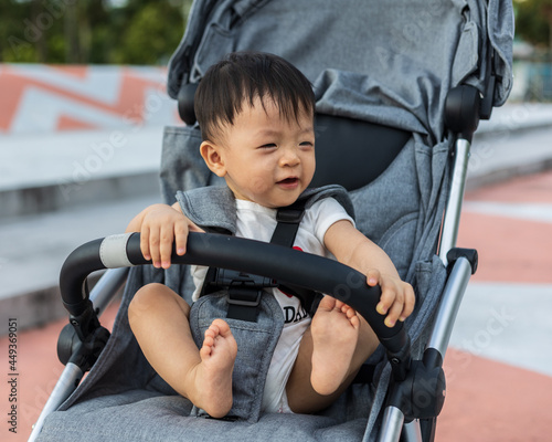 portrait image of Happy and cute Asian Chinese baby boy sitting on stroller at park during evening