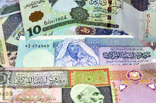 Background of Libyan money dinars banknotes with portraits of Omar Al-Mukhtar and Muammar Gaddafi on some banknotes, selective focus of different banknotes from Libya of different values and years photo