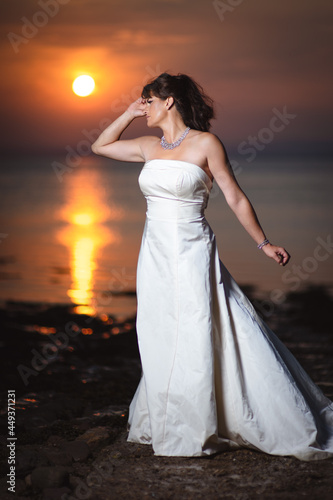 Beautiful bride in white wedding dress at sunset near a beach and the ocean or sea coast in United Kingdom