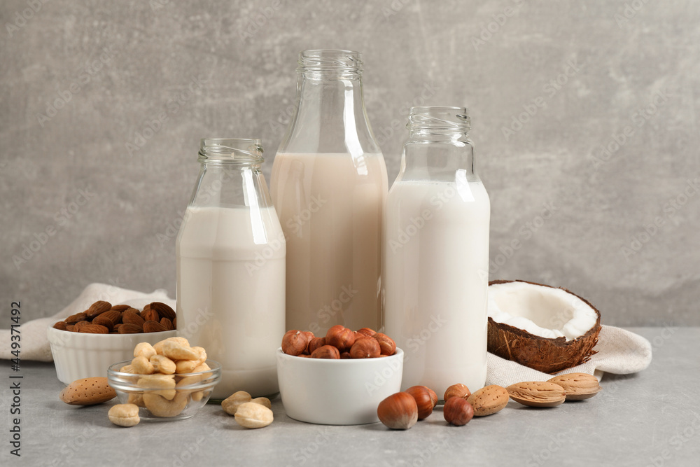 Different nut milks on light grey table Different nut milks on light grey table