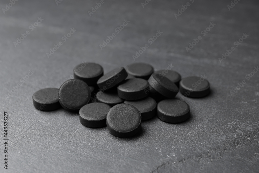 Pile of activated charcoal pills on black table. Potent sorbent Pile of activated charcoal pills on black table. Potent sorbent