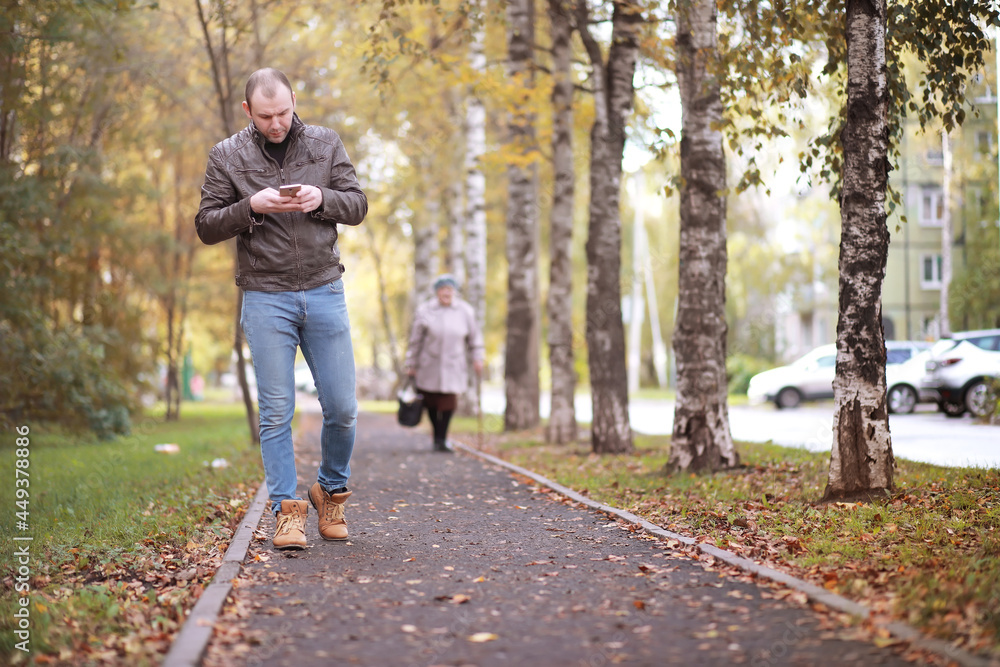 Autumn concept. A man walks through the city. Autumn leaves on the footpath. Autumn concept. A man walks through the city. Autumn leaves on the footpath.