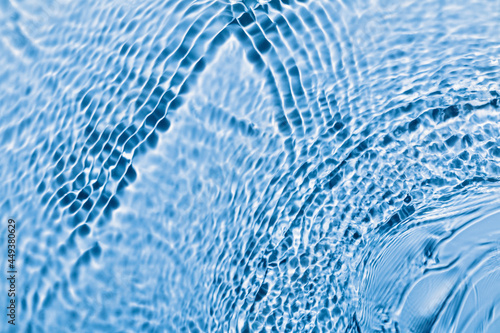 Defocused blue transparent water surface texture with waves and ripples. Abstract background. © Olga