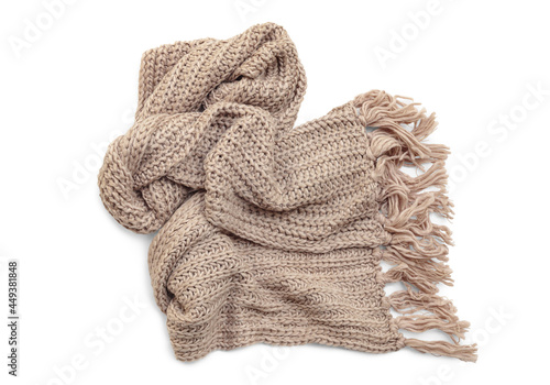 Beige woolen knitted scarf with tassels on white background, top view.