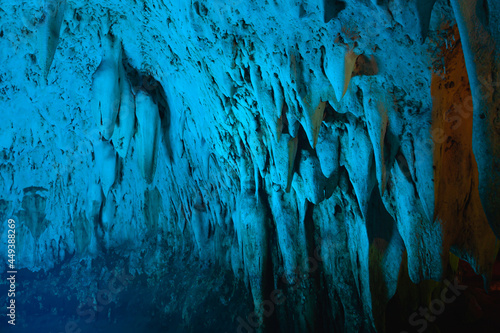 natural stalagmite or stalactite with blue led light in dark cave in mountain
