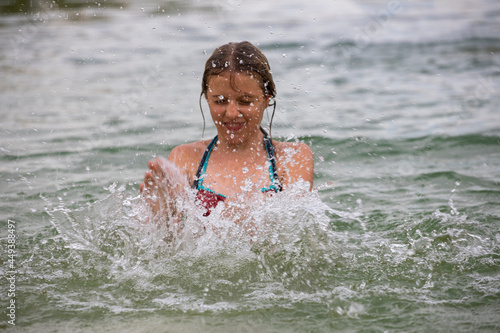 happy teenage girl splashes in water on vacation, horizontal.