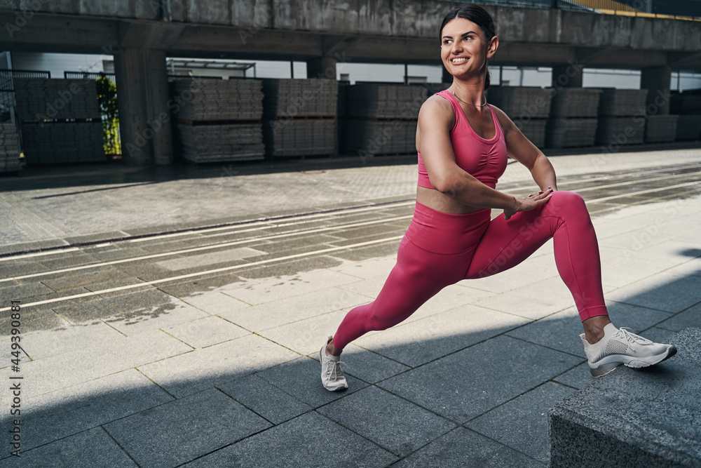 Fototapeta premium Pleased sportive adult woman practising leg stretches