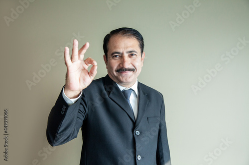 Smart mature older business man with moustache showing a OK sign with his hand wearing suit and tie