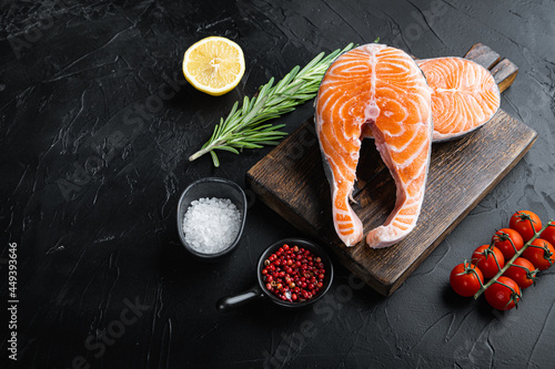 Fesh raw salmon fillet with herbs, over black background with space for text