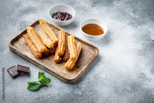 Traditional Spanish dessert churros with sugar and chocolate, on gray background with space for text, copyspace