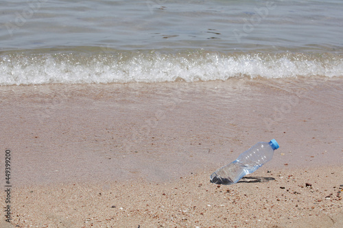 concept of environmental pollution. plastic bottle on the beach near sea. copy space. worldwide crisis of plastic pollution. 