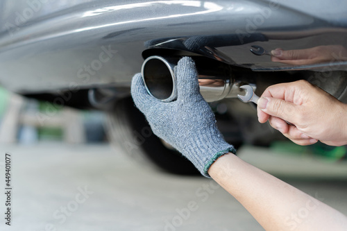 Hand a man catch car exhaust and use open-end wrench for service in concept maintenance car in garage photo