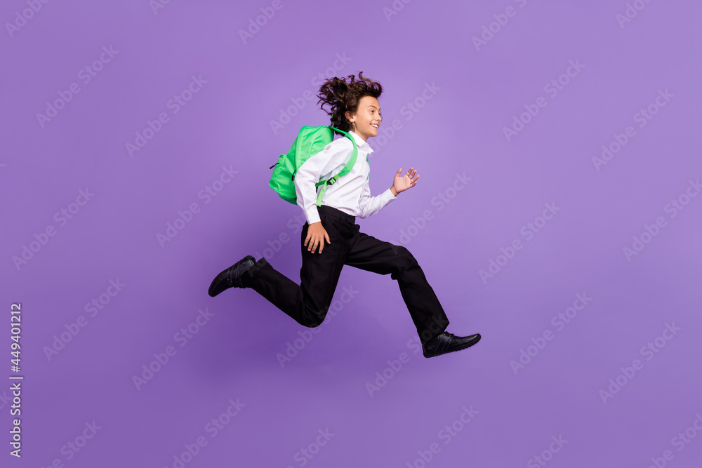 Full size photo of cool little brunet boy run wear bag shirt trousers sneakers isolated on purple background