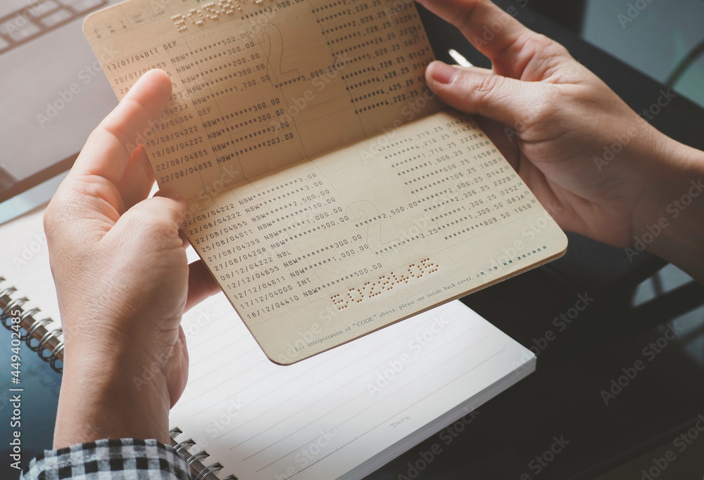 Obraz premium Someone hands holding saving account passbook. financial report passbook saving money finance and business rich concept. financial problems, unemployment due to pandemic covid-19.