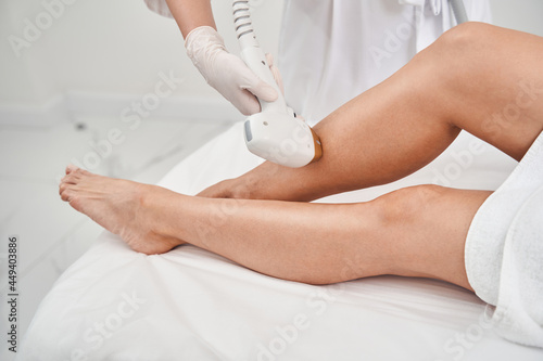 Woman removing hair on feet with laser photo