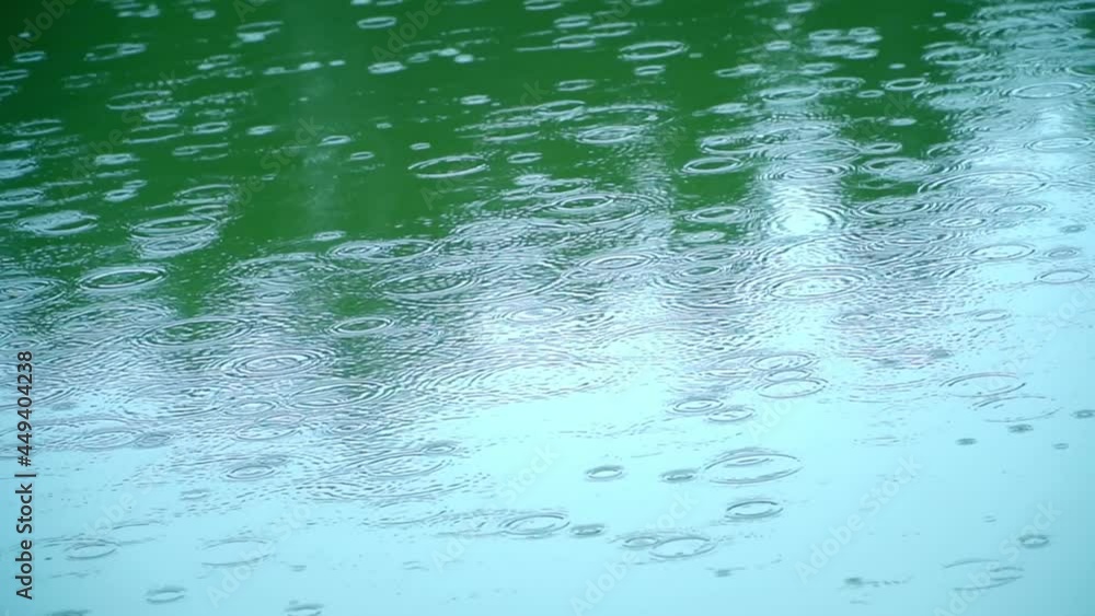Raindrops pitterpattering on the surface of water, creating expanding