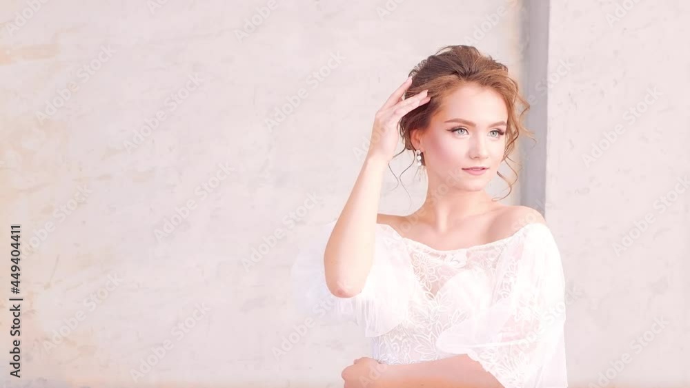 Charming young girl in a white dress posing beautifully. Gorgeous young woman bride on gray isolated background in studio. There is copy space. UHD 4K. Charming young girl in a white dress posing beautifully. Gorgeous young woman bride on gray isolated background in studio. There is copy space. UHD 4K.