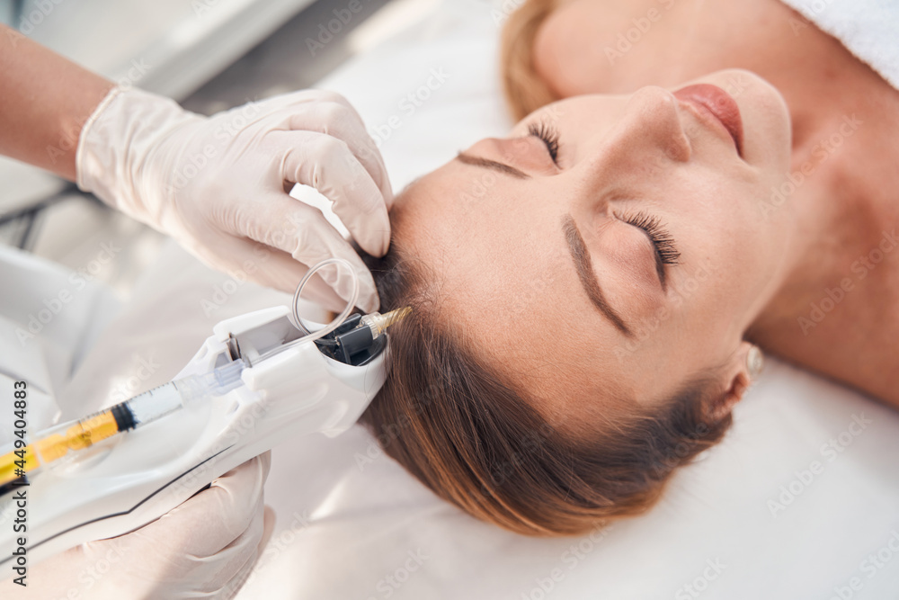 Serene woman during procedure of head mesotherapy Serene woman during procedure of head mesotherapy